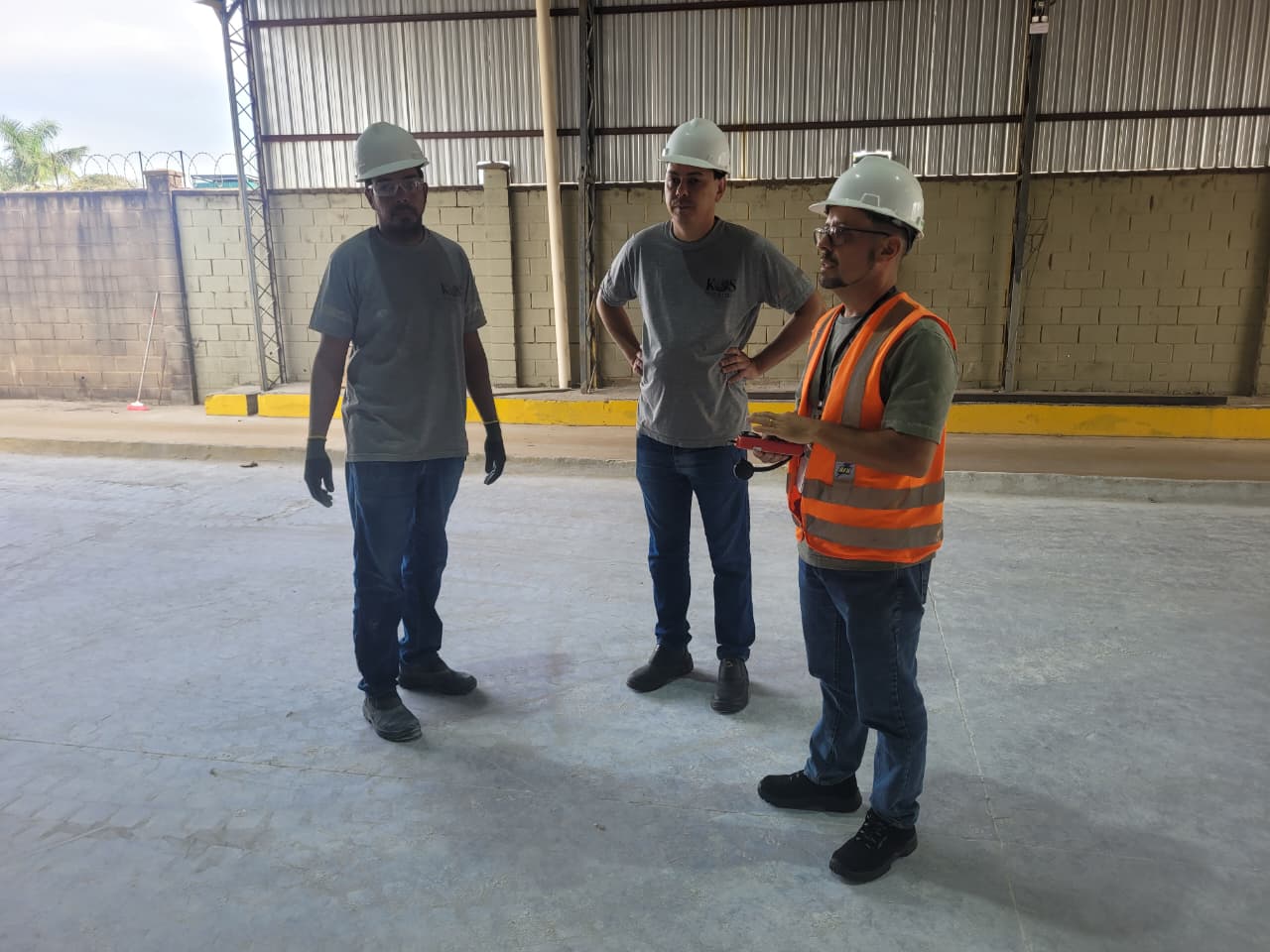 Equipe da ErgoBR discutindo plano de ergonomia dentro de galpão industrial